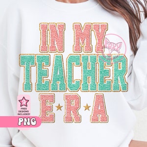 May include: A white sweatshirt with the text "In My Teacher Era" in pink, teal, and gold glitter lettering. The text is in a varsity style font.