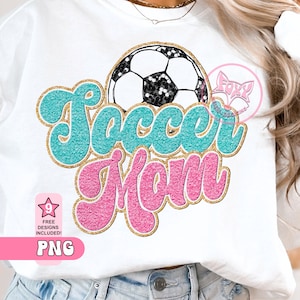 May include: A white t-shirt with a teal and pink graphic that says "Soccer Mom" with a gold glitter outline. A black and white soccer ball with gold glitter is above the text.