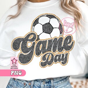 May include: A white sweatshirt with a black and gold glitter design that says "Game Day" with a black and white soccer ball above the text.
