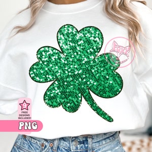 Puede incluir: Sudadera blanca con un gran diseño de trébol verde brillante. El trébol está lleno de purpurina verde y delineado en negro. La imagen también incluye el texto "9 FREE DESIGNS INCLUDED! PNG".