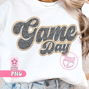May include: A white t-shirt with a black and gold glitter design that says "Game Day".