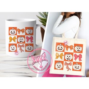 May include: A white ceramic mug and a canvas tote bag featuring a repeating pattern of orange squares with jack-o'-lanterns and bows in various colors. The mug has a pink logo. The tote bag is held by a person.