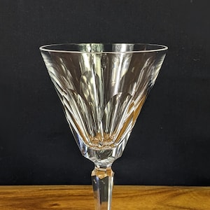 May include: A clear glass wine glass with a cut crystal design. The glass has a tall, slender stem and a wide, shallow bowl.