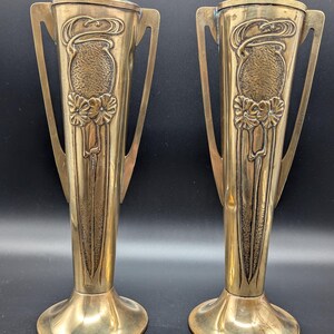 K&ouml;nnte beinhalten: Zwei antike Messingvasen im Jugendstil. Die Vasen haben eine geh&auml;mmerte Oberfl&auml;che und zeigen florale Motive.