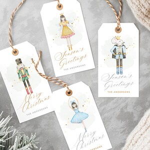 Könnte beinhalten: Vier weiße Geschenkanhänger mit Aquarellillustrationen von Figuren aus dem Ballett Der Nussknacker. Jeder Anhänger hat eine goldene Schnur und trägt den Text "Merry Christmas" oder "Season's Greetings" mit einem Familiennamen.