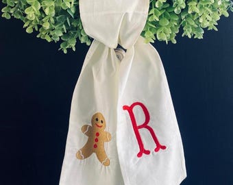 May include: White fabric Christmas stocking with a gingerbread man and the letter "R" embroidered in red.