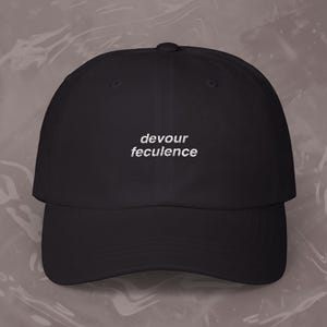 Puede incluir: Una gorra de béisbol negra con la frase "devour feculence" bordada en blanco en la parte delantera.