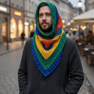 May include: A colorful, crocheted hood and scarf combination. The hood and scarf are made of green, blue, yellow, and orange yarn. The person is wearing a dark gray coat.