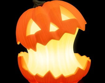 May include: An illuminated orange jack-o'-lantern with a carved face and a large, open mouth. The interior glows with a warm, yellow light, creating a festive Halloween decoration. The pumpkin is set against a black background.