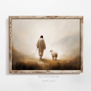 May include: A painting of a man in a white robe walking with a lamb in a misty landscape. The painting is framed in a light wood frame. The text "BELOVED BRUSH digital print" is below the frame.