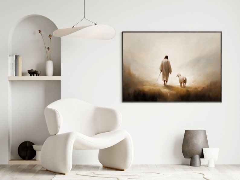 May include: A framed painting depicting a person in a white robe walking with a white sheep in a misty landscape. The painting is hanging on a white wall in a modern living room setting.