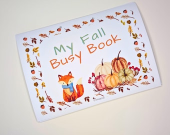 May include: A white rectangular busy book titled My Fall Busy Book in green and orange text. The cover features a watercolor illustration of an orange fox wearing a blue scarf, surrounded by various pumpkins, red berries, and autumn leaves.