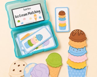 May include: A turquoise plastic storage box containing rectangular cards with ice cream illustrations, labeled Task Box: Ice Cream Matching. Beside the box are loose die-cut paper ice cream scoops, a waffle cone, and a tall stack of scoops.