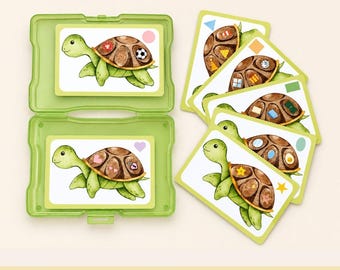 May include: A light green plastic storage case containing two rectangular cards featuring watercolor illustrations of green turtles with brown shells. Four additional turtle cards are fanned out to the right, each displaying different shapes.