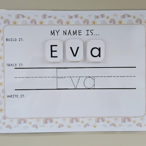May include: A white educational board featuring the name "Eva" in magnetic letters. The board has sections for building, tracing, and writing the name, with a border decorated with rainbows and suns.