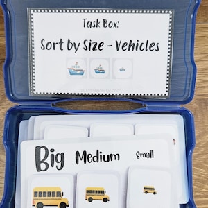 May include: A blue plastic task box labeled "Sort by Size - Vehicles" with cards featuring illustrations of buses and boats. The cards are labeled "Big," "Medium," and "Small." The box is open, revealing the contents.