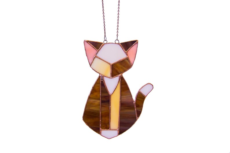 K&ouml;nnte beinhalten: Ein Buntglas-Katzen-Sonnenf&auml;nger mit braunem, wei&szlig;em und rosafarbenem Design. Die Katze h&auml;ngt an einer Kupferkette.