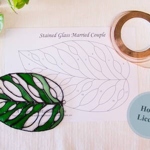 May include: A stained glass leaf with green and white glass pieces, a pattern template, copper foil tape, and a Hobby Licence label.