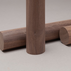 May include: Three wooden dowels, all the same diameter, but different lengths. The dowels are a rich brown color with a natural wood grain.