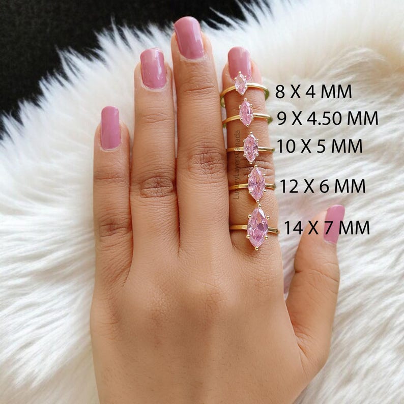 May include: Five gold rings with pink marquise-shaped stones of different sizes. The rings are displayed on a hand, with the sizes of the stones labeled in millimeters. The sizes are 8 x 4 mm, 9 x 4.50 mm, 10 x 5 mm, 12 x 6 mm, and 14 x 7 mm.