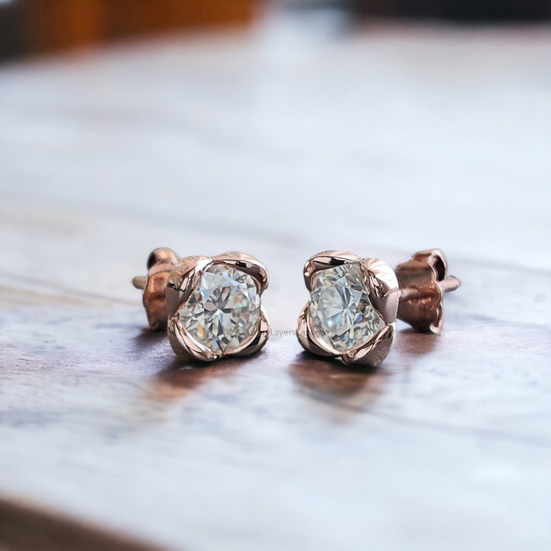 May include: A pair of rose gold stud earrings with a clear round gemstone in each earring.