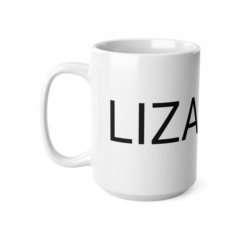 May include: A white ceramic mug with a large, black sans-serif font spelling out 'LIZA' is shown in a three-quarter view. The mug has a C-shaped handle. The mug is a standard 15-ounce size. The background is pure white.