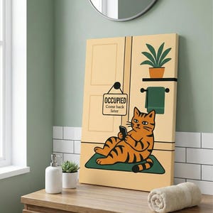 May include: A canvas print depicting a cartoon cat with orange and black stripes, using a phone while lounging on a green mat. The print shows a bathroom scene with a door, a plant, and a sign that reads "OCCUPIED Come back later."