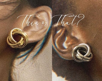 Op de afbeelding: Twee close-ups van een oor met een knoopvormige oorring, een gouden en een zilveren. De tekst "This or That?" staat boven de oorbellen.