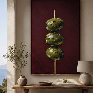 May include: A rectangular wall art piece featuring a vertical painting of three green olives stacked on a wooden skewer against a deep burgundy background. The olives are rendered with thick, textured impasto brushstrokes, creating a three-dimensional appearance. The artwork is framed in a thin, light-coloured wooden frame, highlighting the contrast between the dark red backdrop and the vibrant green of the olives.
