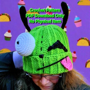 May include: A bright green crochet beanie featuring two tall black antennae, a large white circular eye, a black stitched eyebrow, and a pink tongue sticking out. The text Crochet Pattern PDF Download Only No Physical Item is visible.