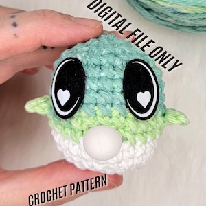 Puede incluir: Patrón de crochet para un juguete amigurumi verde y blanco con ojos negros y corazones blancos. El juguete tiene una nariz de botón blanco. El texto "DIGITAL FILE ONLY" y "CROCHET PATTERN" es visible en la imagen.