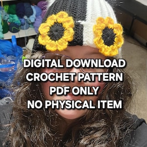 Puede incluir: Un gorro de ganchillo en blanco y negro con detalles de girasoles amarillos y un pomp&oacute;n blanco. El gorro tiene el texto "DESCARGA DIGITAL PATR&Oacute;N DE GANCHILLO S&Oacute;LO PDF NING&Uacute;N ART&Iacute;CULO F&Iacute;SICO".