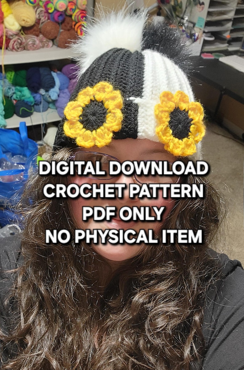 Puede incluir: Un gorro de ganchillo en blanco y negro con detalles de girasoles amarillos y un pomp&oacute;n blanco. El gorro tiene el texto "DESCARGA DIGITAL PATR&Oacute;N DE GANCHILLO S&Oacute;LO PDF NING&Uacute;N ART&Iacute;CULO F&Iacute;SICO".