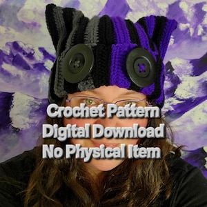 May include: A handmade crochet hat with a unique design. The hat features black, gray, and purple sections, adorned with large black buttons. The text on the image reads "Crochet Pattern Digital Download No Physical Item."