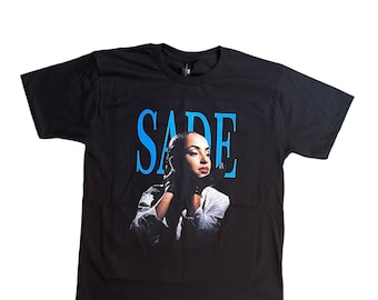 May include: Black t-shirt with a blue "SADE" graphic and a photo of Sade in a white polka dot shirt.