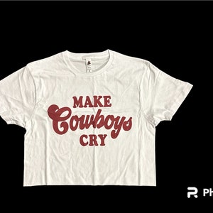 May include: White cropped t-shirt with a red graphic that says "MAKE cowboys CRY"