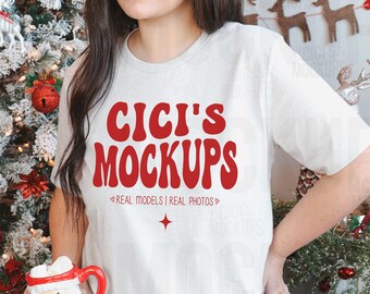 May include: A white t-shirt with the text "CICI'S MOCKUPS" in red lettering. The text is in a retro font style. Below the text is the phrase "REAL MODELS | REAL PHOTOS" in smaller red lettering.