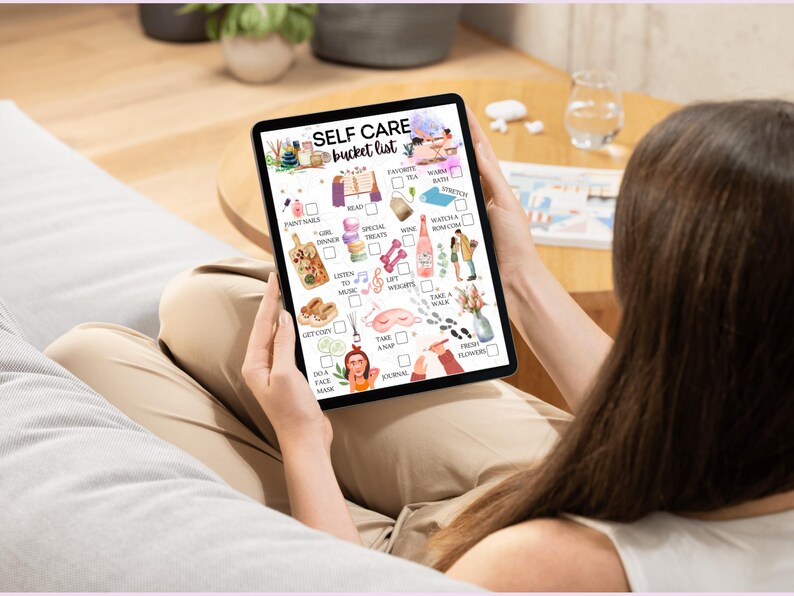 May include: A digital tablet displaying a self-care bucket list with illustrations of various activities, such as reading, taking a bath, and listening to music. The list includes items like paint nails, girl's trip, special treats, read, warm bath, stretch, watch a rom com, wine, lift weights, take a walk, fresh flowers, do a face mask, journal, and take a nap.