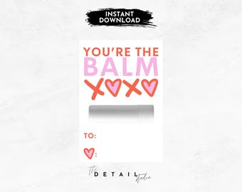 May include: A printable Valentine's Day card with the text "You're the Balm" in pink and red lettering with hearts and a blank space for a lip balm. The card also has a space to write "To:" and "♡:"