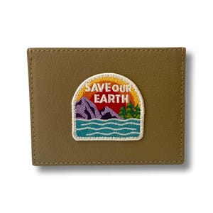 May include: A brown leather wallet with an embroidered patch that says "Save Our Earth". The patch features a mountain range, a sun, and a lake.