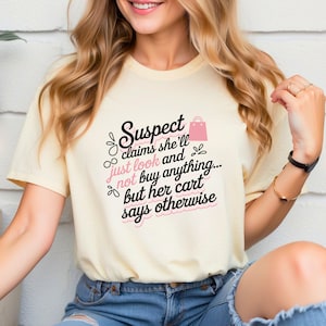 May include: A light yellow t-shirt with a black and pink graphic that says "Suspect claims she'll just look and not buy anything... but her cart says otherwise".