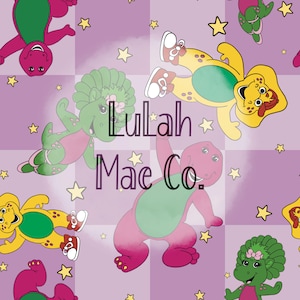 May include: A repeating pattern featuring cartoon dinosaurs in shades of purple, green, and yellow, with star accents. The text "Lulah Mae Co." is overlaid on the design. The dinosaurs are in various poses against a checkered background.
