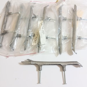 May include: A collection of silver-toned metal drawer pulls shaped like twigs, each featuring two threaded mounting bolts. Several pulls are individually sealed in clear plastic bags, with one loose pull displayed in the foreground.