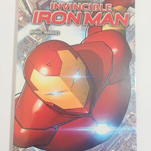 May include: A comic book cover for Invincible Iron Man, featuring a red and gold Iron Man suit in a dynamic pose. The title is prominently displayed with the Marvel logo and the word "Reboot". The cover includes text: "This is a brave new run for the Armored Avenger, and it's off to a roaring start."