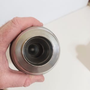May include: A stainless steel insulated tumbler with a wide mouth and a silver finish. The tumbler has a cylindrical body and a rounded top, designed to keep beverages hot or cold. The interior is dark, suggesting insulation.