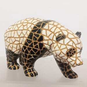 May include: A ceramic panda bear figurine with a mosaic-like design. The panda has a black and white pattern with gold accents. The bear is in a walking pose, showcasing its detailed craftsmanship.