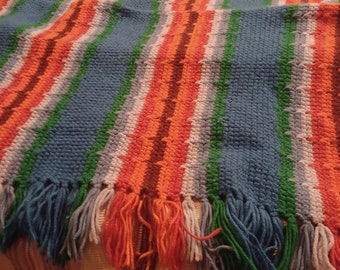 May include: A multi-colored striped crocheted throw blanket with fringe. The blanket is made with blue, green, orange, white, and brown yarn.