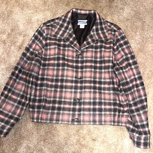 May include: A pink and black plaid button-up jacket with a collared neckline. The jacket has a single button closure and long sleeves. The label "Pendleton" is visible on the inside of the collar.