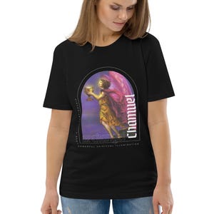 Puede incluir: Camiseta negra con un gráfico de un ángel sosteniendo un cáliz dorado. El gráfico está enmarcado en un arco negro con la palabra "Chamuel" escrita verticalmente en texto blanco. El texto "Angel of Love & Harmony" está escrito en texto blanco debajo del arco. El texto "Powerful Spiritual Illumination" está escrito en texto blanco debajo del ángel.