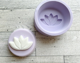 May include: Two purple silicone molds for making resin crafts. One mold is a round dish with a lotus flower design. The other mold is a round disc with a raised lotus flower design.